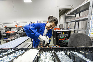 A woman assembles INVENOX battery system components with a cordless screwdriver