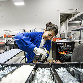 A woman assembles INVENOX battery system components with a cordless screwdriver