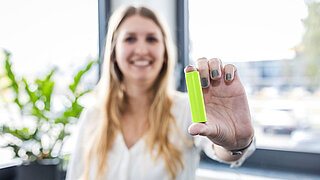 Frau hält CONCHIFERA-Batteriezellenmodul in der Hand und zeigt es in die Kamera.