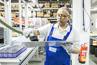 A man cleans a module circuit board from an INVENOX battery system.